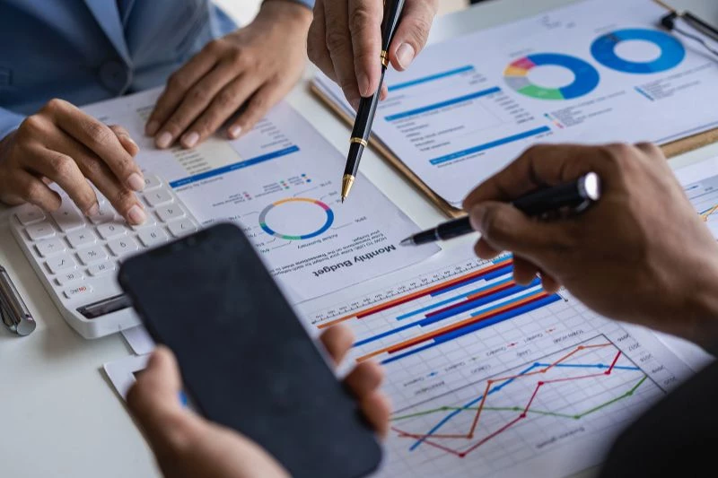 Analyse de graphiques financiers et de documents lors d'une réunion de travail sur la diligence raisonnable.